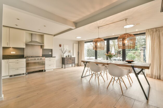 An open space with a dining area and a small corner kitchen in white in a cozy house