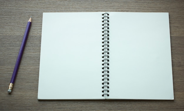 open spiral notebook and pencil on dark wood background