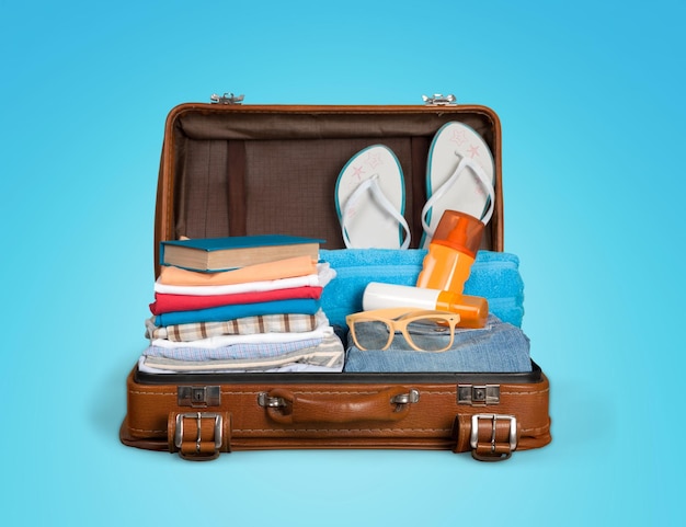 Photo open suitcase with traveler's belongings on color background, top view. space for text