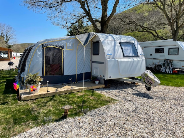 An open tent in front of a travel trailer at a caravan\
campsite.