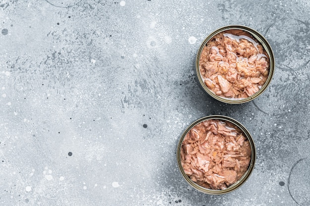 Open tin can with canned tuna fish. Gray background. top view. Copy space.