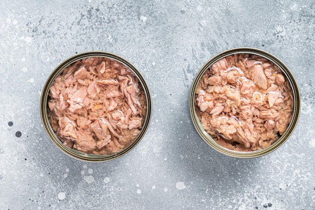 Open tin can with canned tuna fish. Gray background. top view.