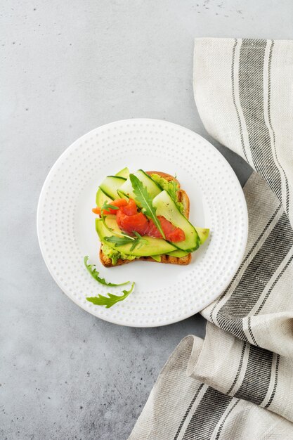 Open toast met forel, zalm, avocado, komkommer en rucola