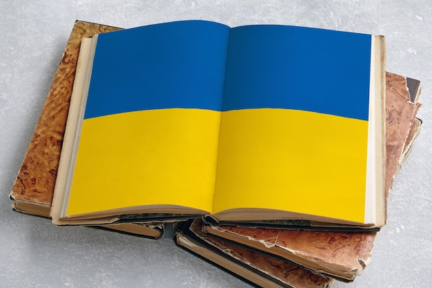 An open vintage book with a printed flag of Ukraine on a light concrete table