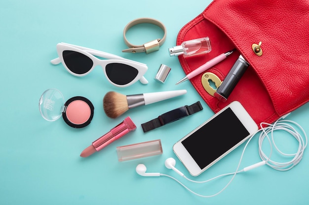 Open vrouw mode tas met cosmetica en levensmiddelen op blauwe achtergrond