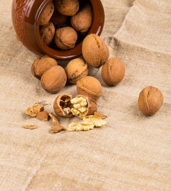 Open walnuts closeup in brown pot on sackcloth