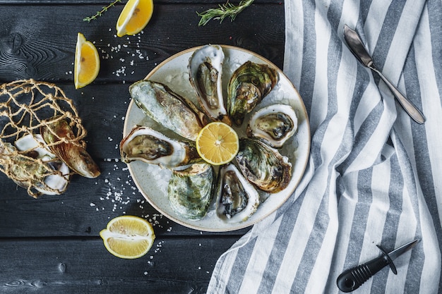 Open wet oysters on a plate with lemon