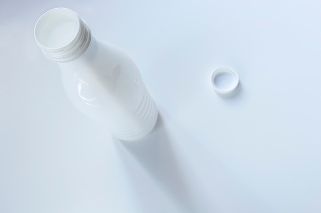 Открытая белая пластиковая бутылка молока на белом фоне