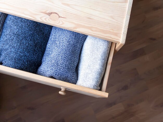 Open wooden dresser drawer with warm knitted woolen clothes\
home vertical storage wardrobe organisation trendy colors