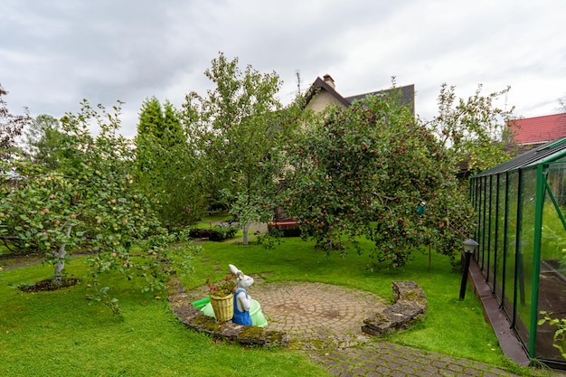 Gazebo in legno aperto nel giardino con alberi di mele e fiori sfondo del paesaggio estivo