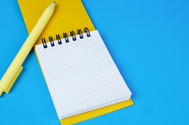 An open yellow notepad with tearoff pages a blank page with a yellow pen on a blue background Place for text