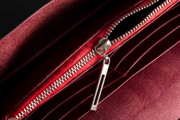 An open zipper on a red leather item or wallet