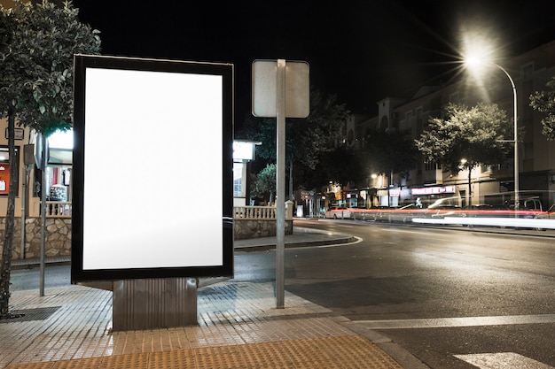 Openbaar informatiebord met vervaagde voertuigverlichting in de stad