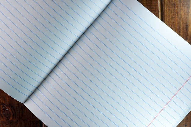 Opened blank notebook with white sheets in a ruler on a brown wooden background close-up