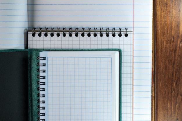 Opened blank notebooks with white sheets in a ruler and a box on a brown wooden background close-up