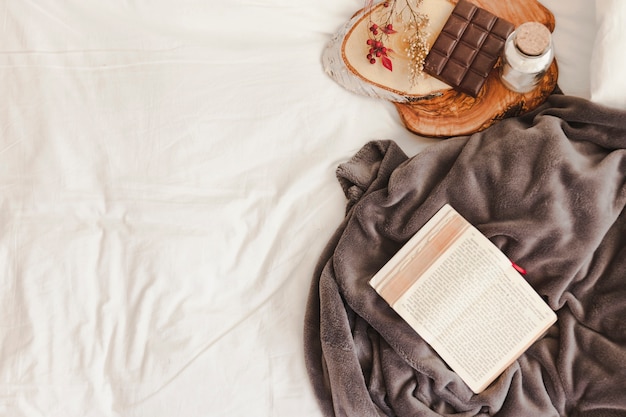 Opened book and blanket near chocolate bar