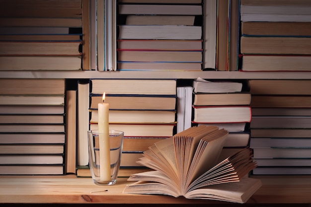 The opened book and the burning candle against from books