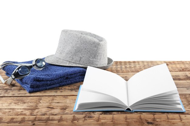 Opened book hat and towel on wooden table