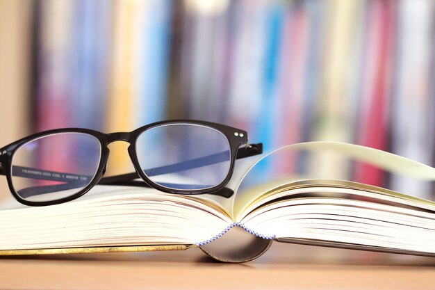 opened book page and  reading eyeglasses with  blurry bookshelf background for education 