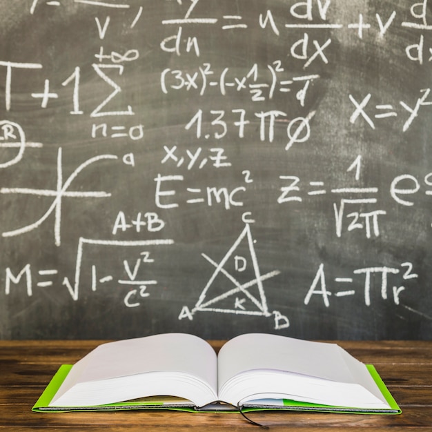 Photo opened book on table near blackboard