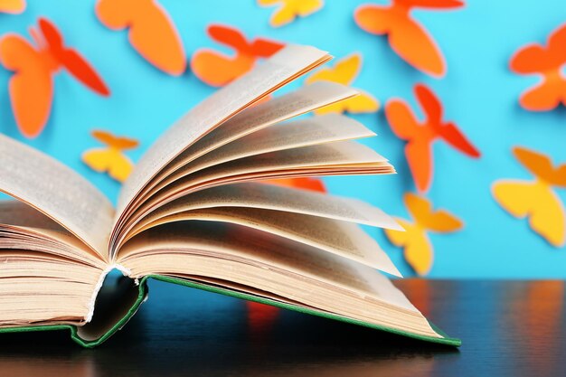 Photo opened book on wooden table on butterflies background