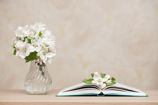 Opened books and a vase with white flowers on the table against the background of the wall
