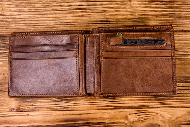 Opened brown leather wallet on rustic wooden table. Top view