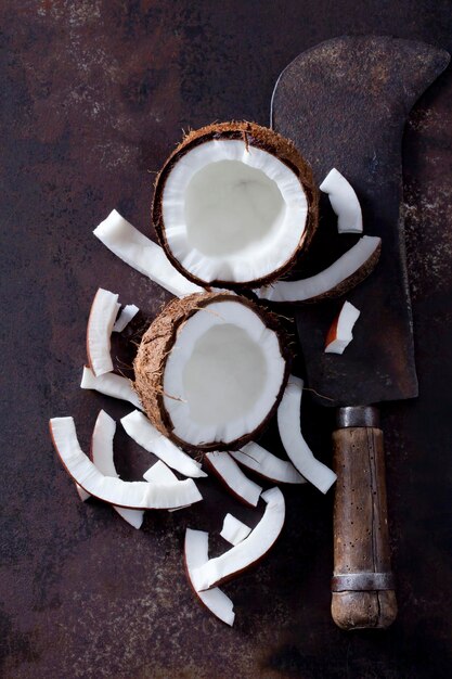 Opened coconut, cocontu pieces and an old cleaver