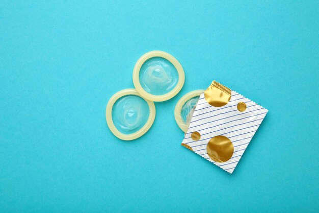 Opened condom in pack on blue background A condom use to reduce the probability of pregnancy or sexually transmitted disease