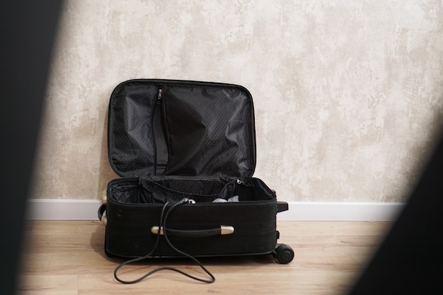 写真 灰色の背景にさまざまなもののために空の黒いスーツケースを開きました。旅行準備のコンセプト