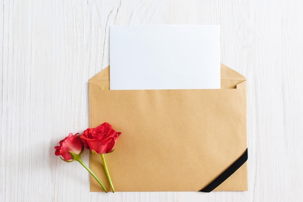 Фото Открытый конверт с чистым листом бумаги и черной лентой с двумя розами