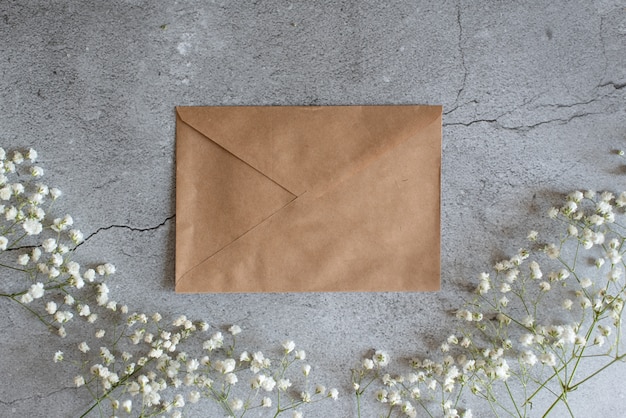 Opened envelope with flowers arrangements on pink background, top view. Festive greeting concept