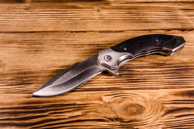 Opened folding knife on rustic wooden table