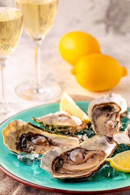 Photo opened fresh oysters on a blue plate served with lemon and ice