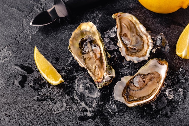 Opened fresh oysters on a dark table served with lemon and ice