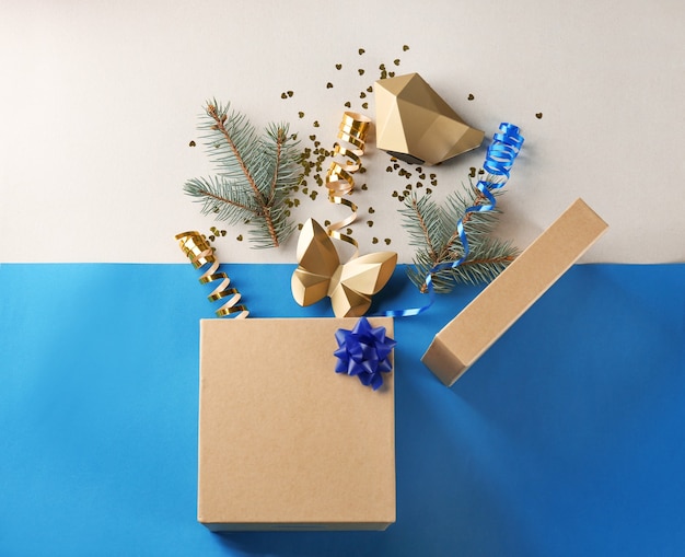 Opened gift box with fir branches and Christmas decorations on color surface, top view