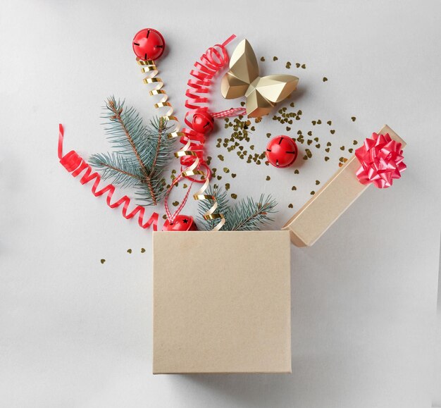 opened gift box with fir branches and christmas decorations on light background, top view