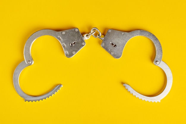 Opened handcuffs on yellow background