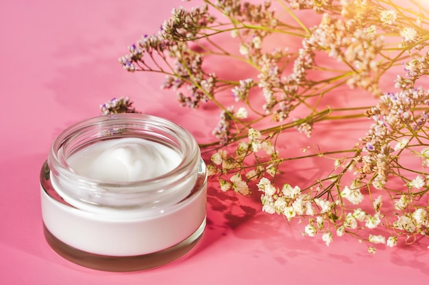 Opened jar of facial or body cream on the pink background. Nature skin care. High quality photo