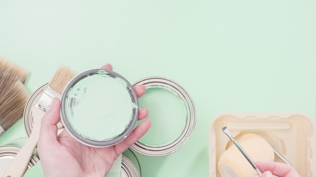 Opened metal paint can with blue color paint and oother paint supplies.