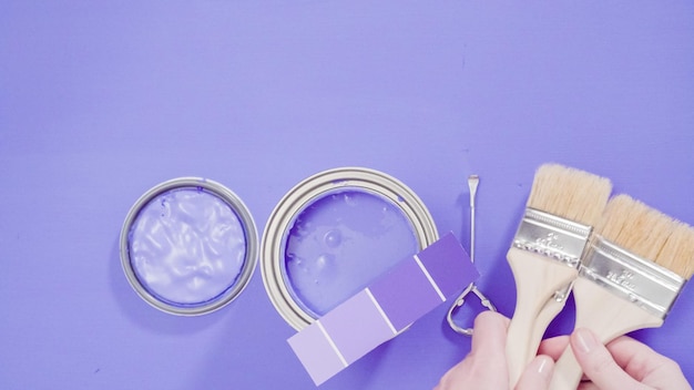 Barattolo di vernice in metallo aperto con vernice viola e campioni di vernice.