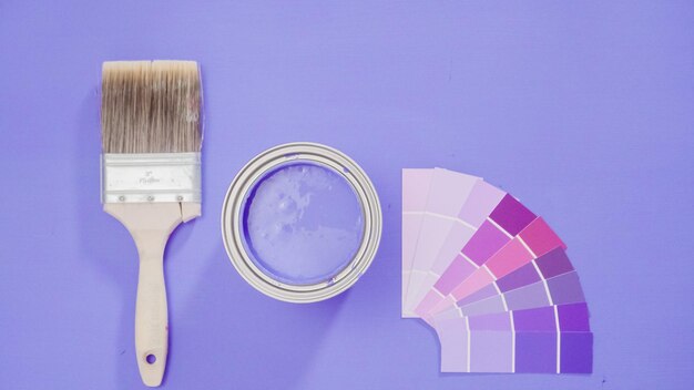 Opened metal paint can with violet paint and paint swatches.