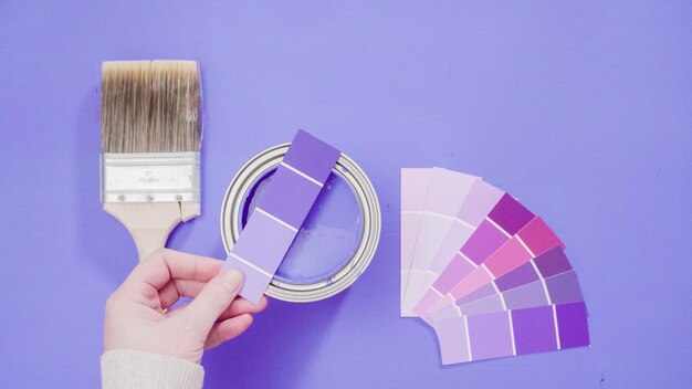 Opened metal paint can with violet paint and paint swatches.