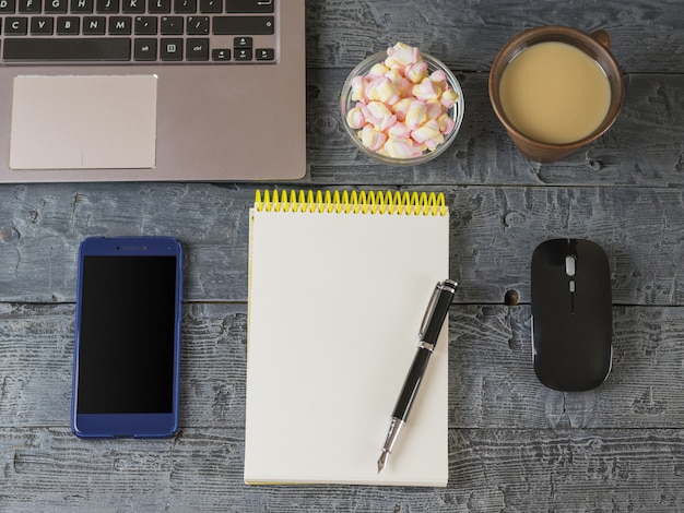 Opened the notebook, laptop, fountain pen and mouse on a dark wooden table