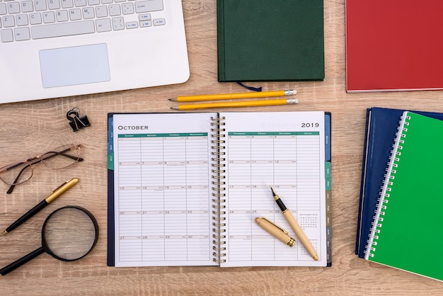 Opened notepad with laptop on wooden table