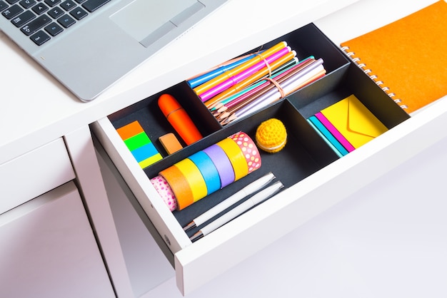 Opened office desk drawer with stationary