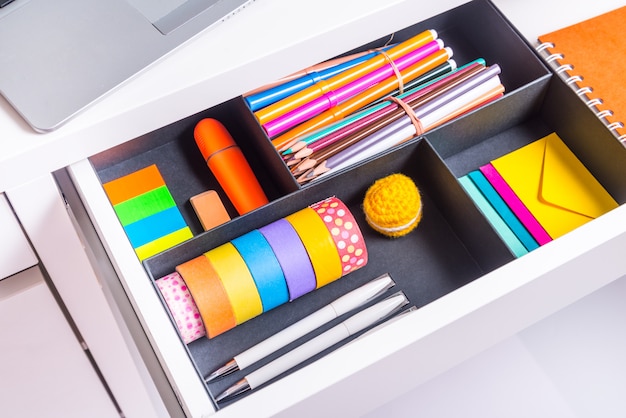 opened office desk drawer with stationary