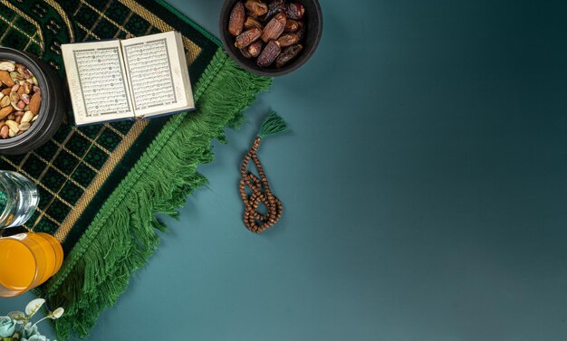 Opened quran near dates concept of ramadan kareem on dark green background