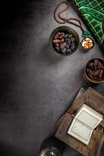 Opened quran near dates concept of ramadan kareem on dark textured background