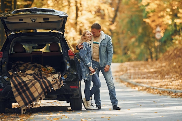 Opened trunk couple standing on the road in park near
automobile